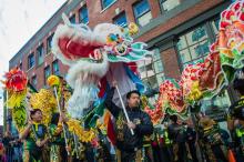 Several performers hold up a lion and dragon in front of the Wing Luke Museum