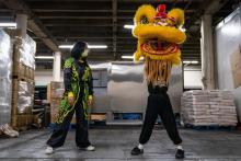 Tina Le, left, and Cooper Nguyen, right, take turns moving with the lion head at a Little Saigon grocery warehouse rented by the Mak Fai Kung Fu Dragon & Lion Dance Association in December