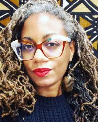 Headshot of a woman wearing glasses. African mudcloth in background.