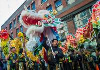 Several performers hold up a lion and dragon in front of the Wing Luke Museum