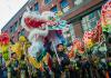 Several performers hold up a lion and dragon in front of the Wing Luke Museum