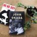 View from above of two books, NO-NO BOY and JOHN OKADA, next to a potted plant on a wooden tabletop